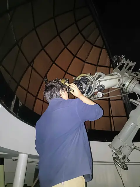 Observer using a telescope in an observatory
